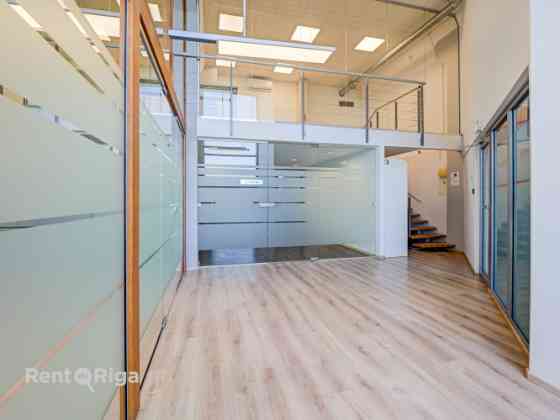 A spacious and bright loft-style office featuring an open-plan workspace and separate private office Рига