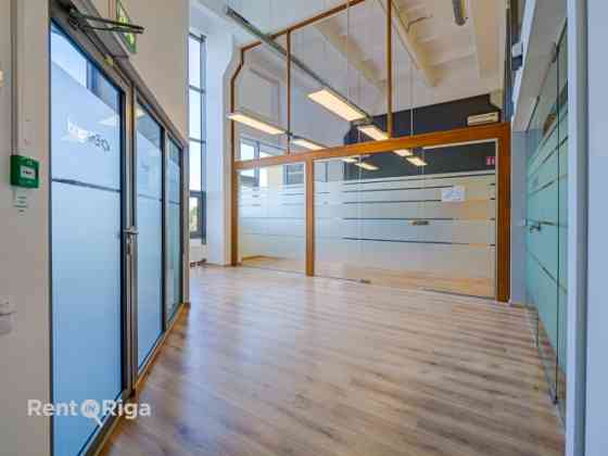 A spacious and bright loft-style office featuring an open-plan workspace and separate private office Рига